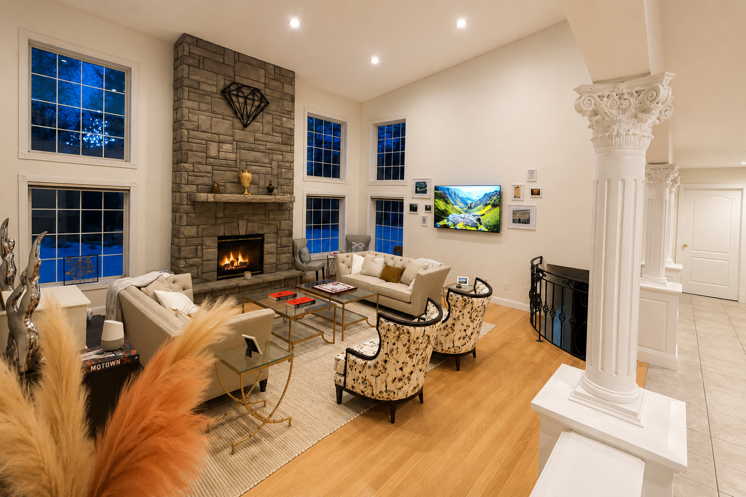 Luxury two-story great room at The Estate at Rebecca's Fountain featuring a floor-to-ceiling stone fireplace, grand columns, open-concept design and elegant entertaining space.
